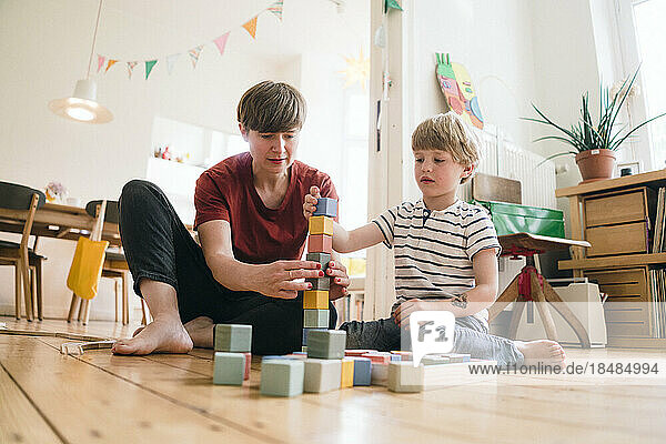 Mutter und Sohn balancieren zu Hause Spielzeugblöcke