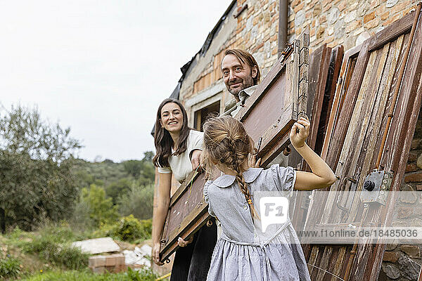 Mädchen hilft Eltern beim Tragen einer Holztür auf der Baustelle