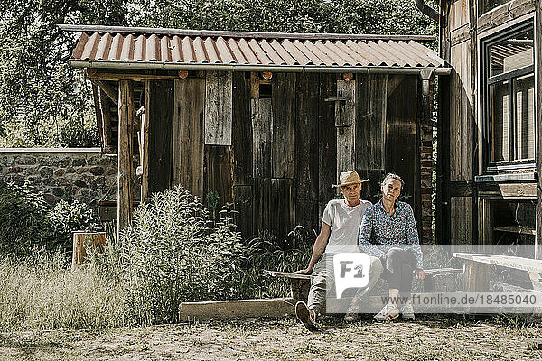 Owner couple sitting on bench outside barn
