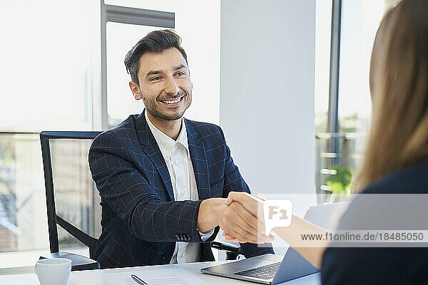 Happy recruiter shaking hand with candidate after interview at office