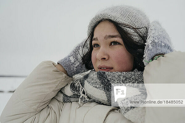 Thoughtful teenage girl wearing knit hat and scarf in winter