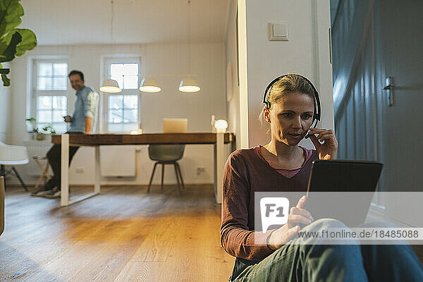 Woman using tablet PC and talking through headset at home office