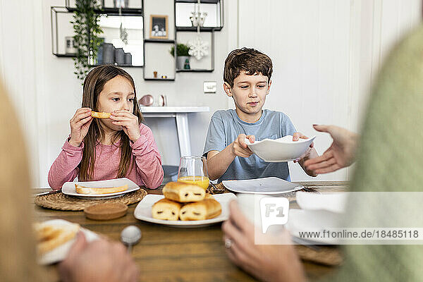 Siblings with mother and father having breakfast together at home
