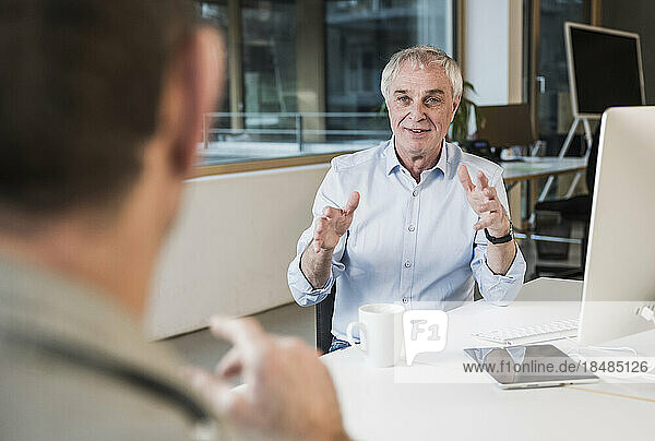 Businessman gesturing and explaining to colleague at office