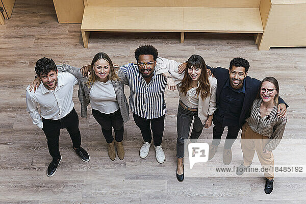 Portrait of happy business team embracing in office