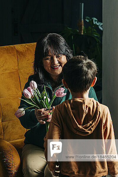Glückliche Großmutter  die ihrem Enkel zu Hause Tulpenblumen schenkt