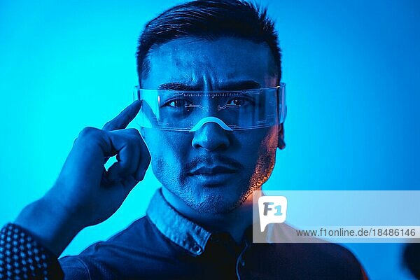 Porträt eines jungen Chinesen mit Neonbrille mit blauem Licht  futuristisches Konzept  Technologie des Cyber Menschen