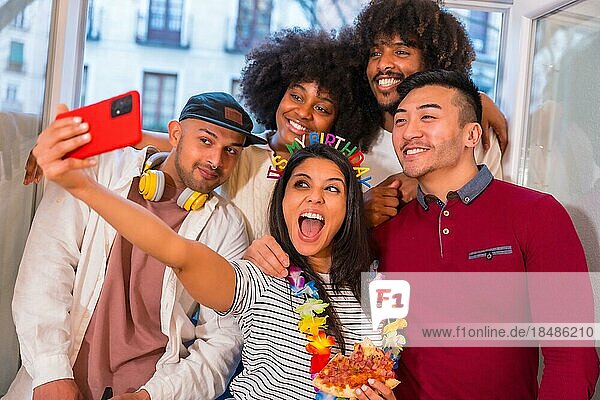 Portrait of a group of friends eating pizza on the terrace at home on a birthday  taking a souvenir selfie