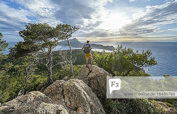 Wanderer auf Felsen  Ausblick auf Berge und Küste mit Meer  im Abendlicht  Wanderung nach La Trapa von Sant Elm  hinten Insel Sa Dragonera  Serra de Tramuntana  Mallorca  Spanien  Europa