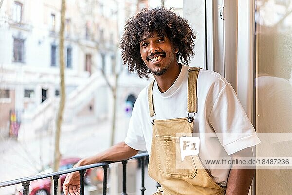 Portrait of a young black ethnic man on a balcony at home  everyday situation  apartment  smiling