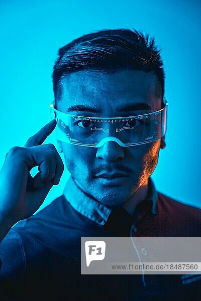 Porträt eines chinesischen Mannes mit Neonbrille mit blauem Licht  futuristisches Konzept  Technologie des Cyber Menschen