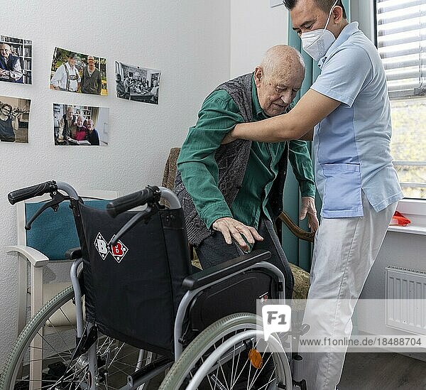 Carer helps old man stand up in a nursing home  Heidelberg  Germany  Europe