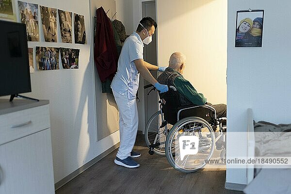 Altenpfleger schiebt einen Rollstuhl im Pflegeheim durch eine Tür  Heidelberg  Deutschland  Europa