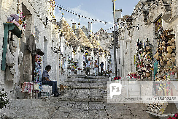 Weiß getünchte Trulli-Häuser und Souvenirläden entlang der Straße in der Altstadt  Alberobello  UNESCO-Weltkulturerbe  Apulien  Italien  Europa