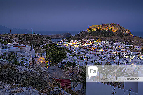 Blick auf Lindos und die Akropolis von Lindos aus erhöhter Position in der Abenddämmerung  Lindos  Rhodos  Dodekanes Inselgruppe  Griechische Inseln  Griechenland  Europa