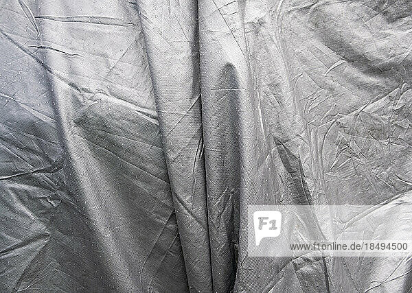 Black and white image  folds of tarpaulin draped across objects.