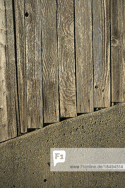 Planks of a wooden fence and concrete wall.