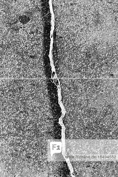 A crack between flagstones painted with a white line  on a concrete sidewalk surface.
