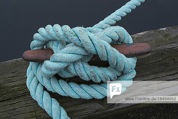 Industrial rope tied around a metal boat cleat.