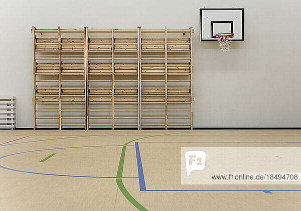 Indoor basketball court at a school. Wooden floor and marked court  a hoop and backboard.
