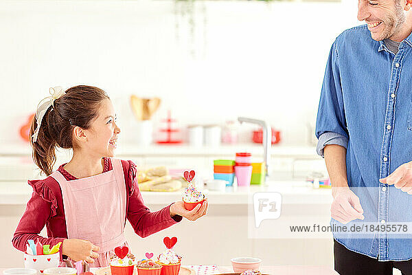 Smiling young girl making sweets with her dad