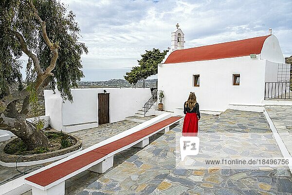Junge Frau mit rotem Rock bei einer kykladischen weiß roten orthodoxen Kirche  Paleokastro Monastery  Mykonos  Kykladen  Griechenland  Europa