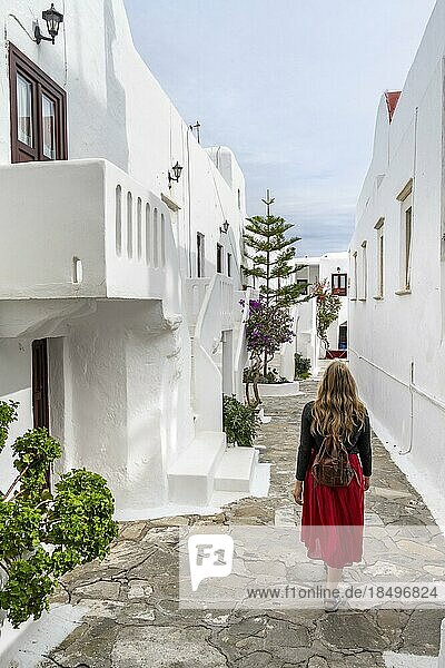 Young woman with red skirt in the alleys of Ano Mera  Cycladic white houses  Ano Mera  Mykonos  Cyclades  Greece  Europe