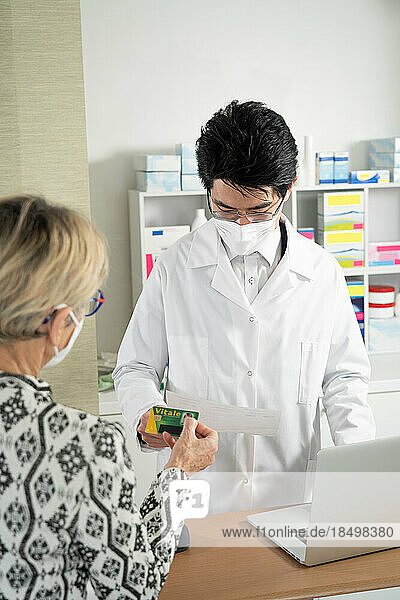 Client presenting her vital card to a pharmacist.