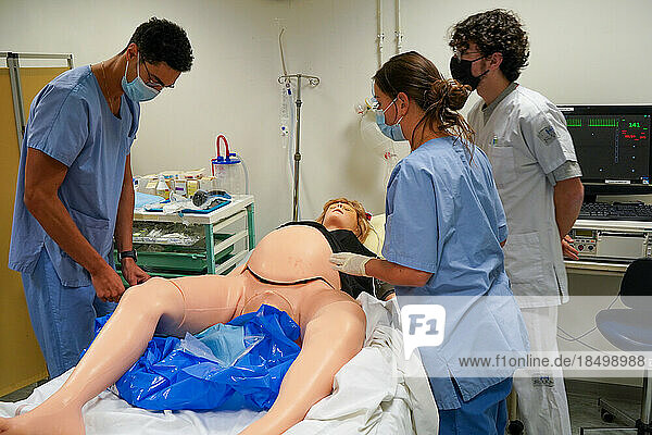 Students facing a post natal emergency follow procedures on a mannequin. This dummy is controlled by operators in an adjoining room. Here  a woman with heavy bleeding following a home birth. Intervention of a student in intensive care.