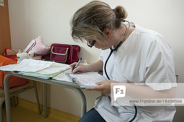 Pediatrician completing the child's medical file and health record.