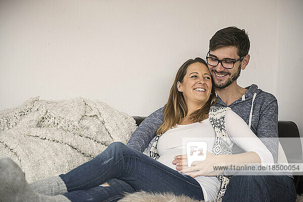 Pregnant woman on sofa with her husband  Munich  Germany