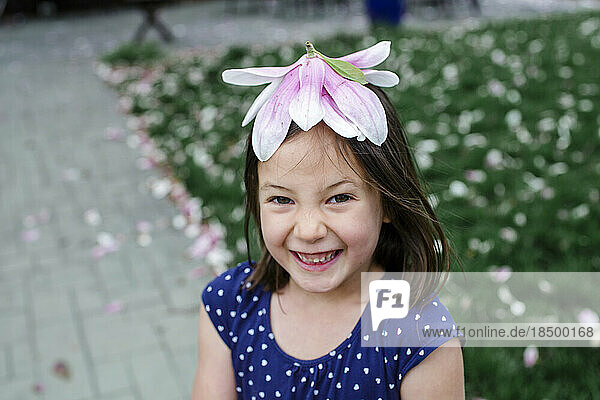 A giggling little girl wears a magnolia blossom for a hat
