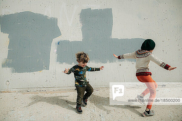 Boy and Girl Dancing in front of Concrete Wall