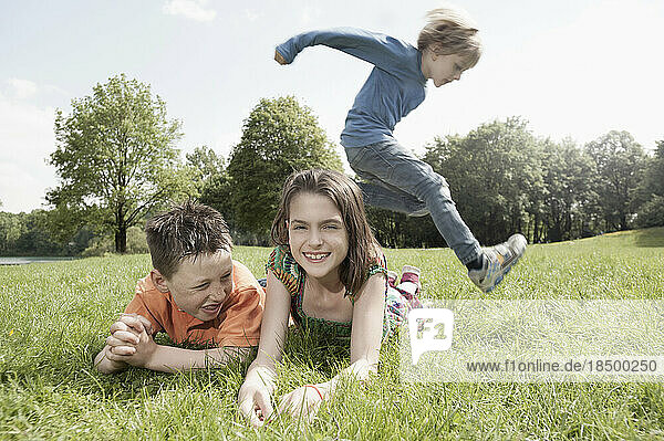 Boy jumping over his friends lying on grass in a park  Munich  Bavaria  Germany