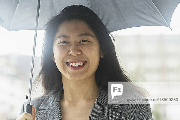 Portrait of a happy young woman under umbrella  Freiburg Im Breisgau  Baden-württemberg  Germany