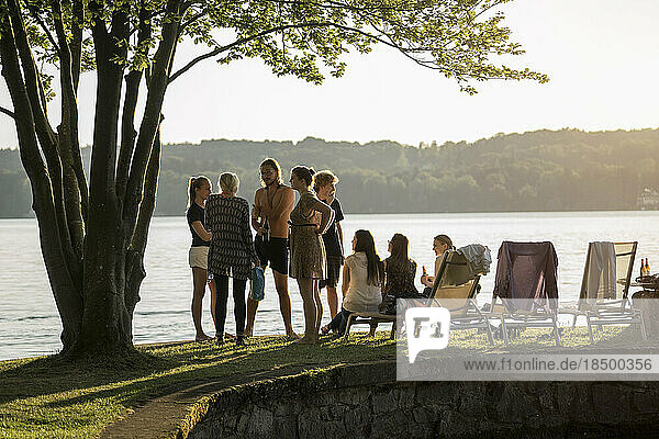 Group of young friends partying at lakeside during sunset  Bavaria  Germany