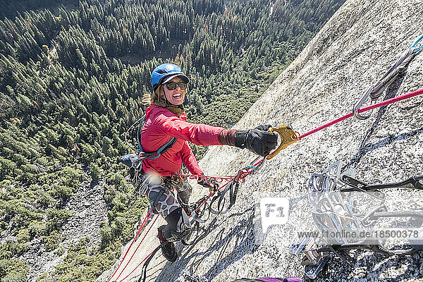 A young woman is all smiles while jumaring on a fixed rope way high up