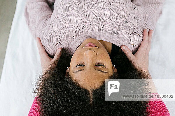 Multiracial Black girl getting craniosacral therapy inside clinic