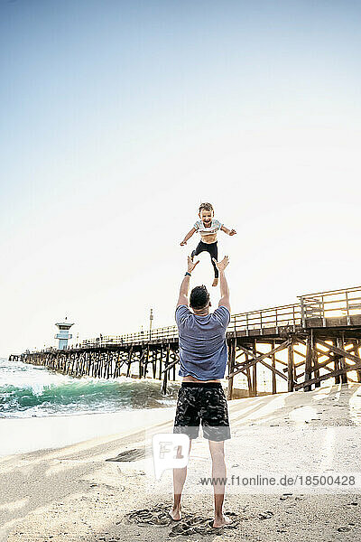 Dad throwing toddler in air at the beach