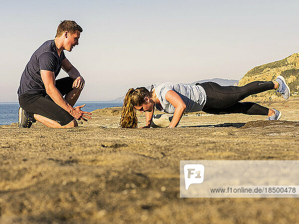 Man with woman doing push-ups on the beach of Azkorri