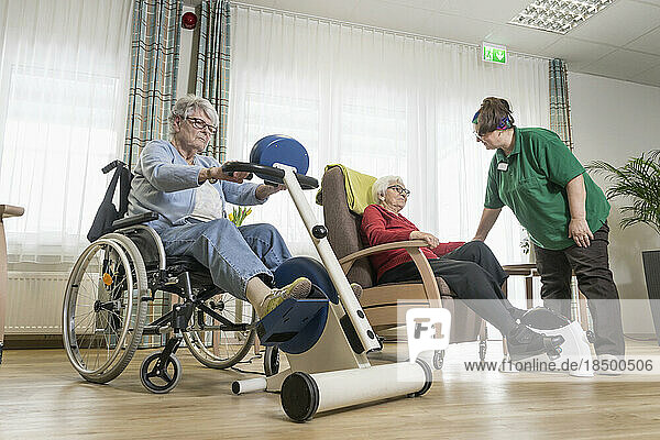 Nurse with senior women exercising on exercise bike in rest home