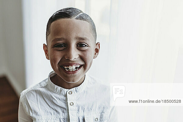 Portrait of young boy smiling at camera in natural light studio