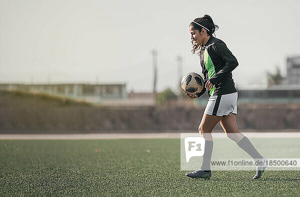 Portrait of latin woman football player holding a football.