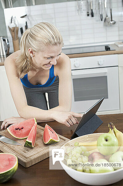 Young woman using digital tablet in the kitchen and smiling  Bavaria  Germany