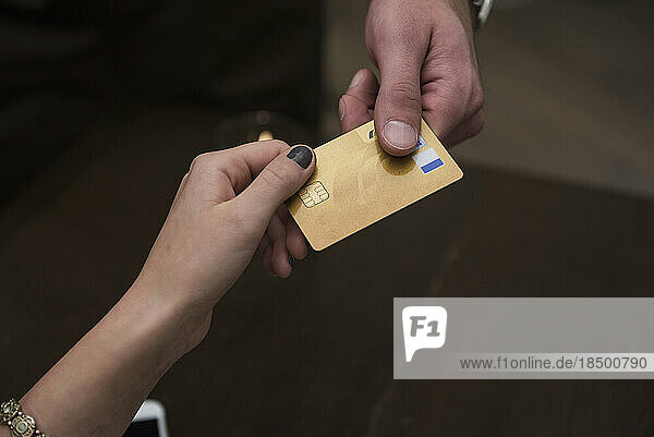 Cropped image of hands holding credit card at restaurant