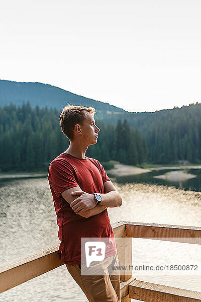 young man is alone near a mountain forest lake