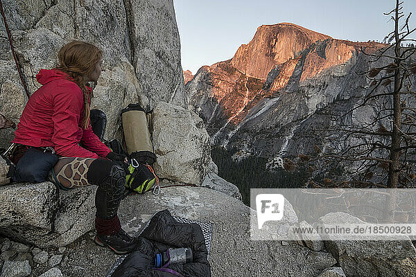 A young woman takes in the sunset on Halfdome from her bivy