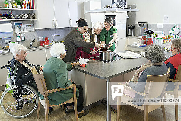 Nurses preparing food with senior inhabitants in rest home