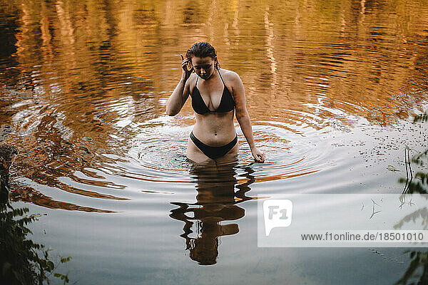 Sensual woman in a bikini walking in river