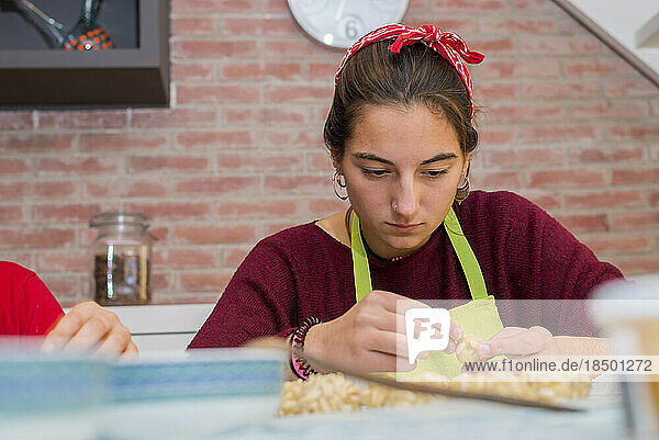 Cheerful teen concentrated working with traditional catalonian p